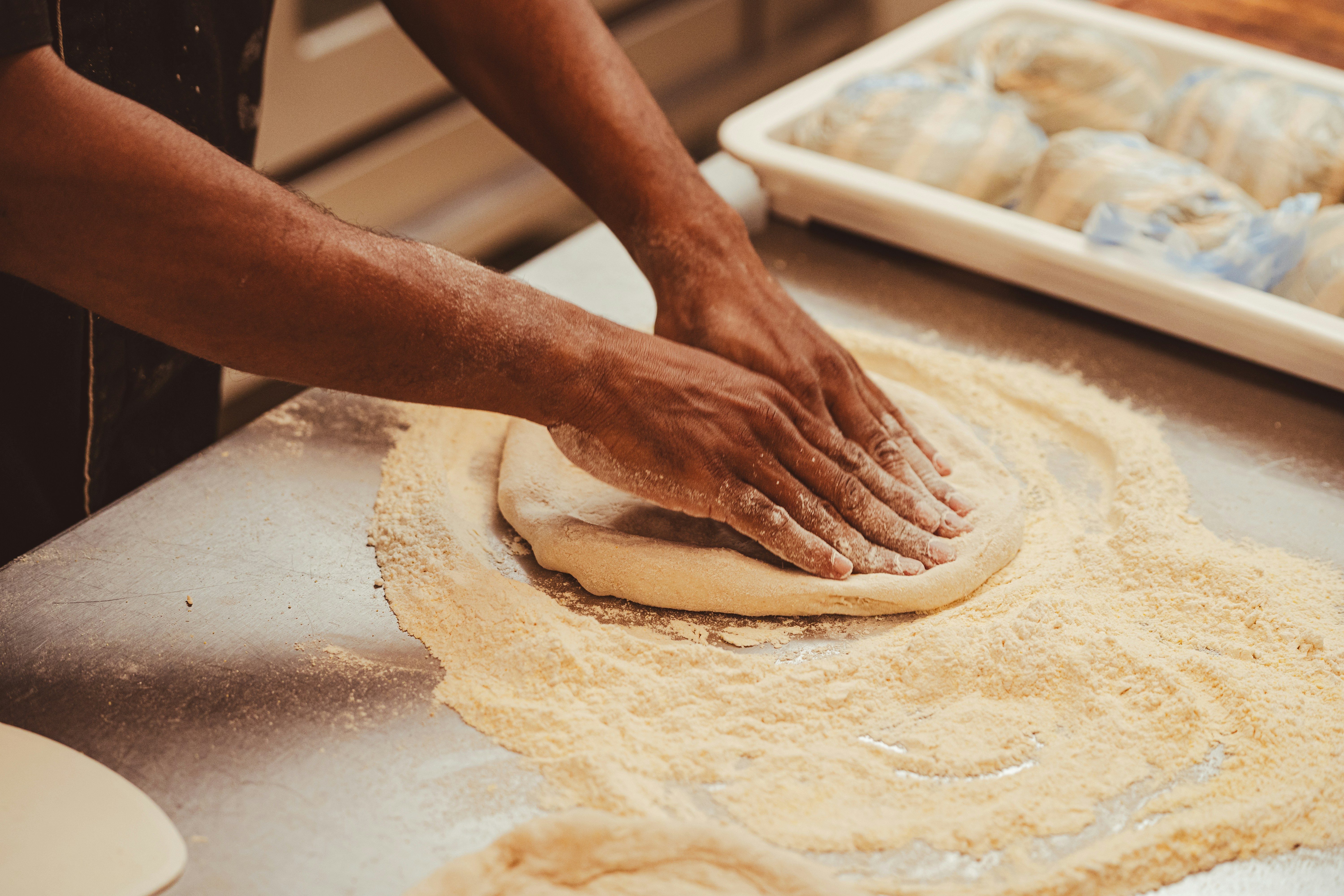 A pizza maker shaping dough on a floured work surface